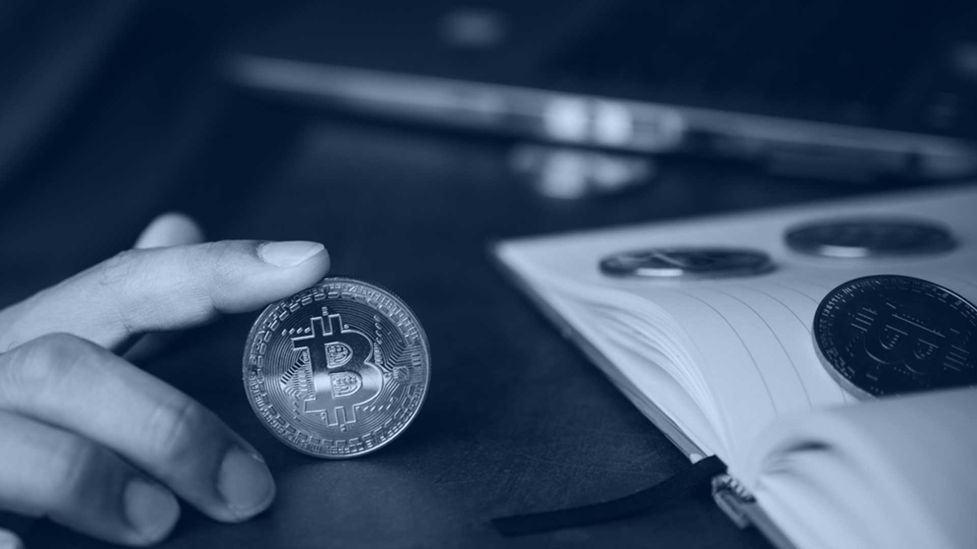 Someone balancing a bitcoin on a table with their index finger