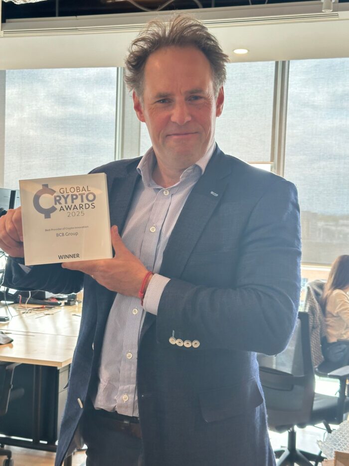 A man holding up and award and smiling